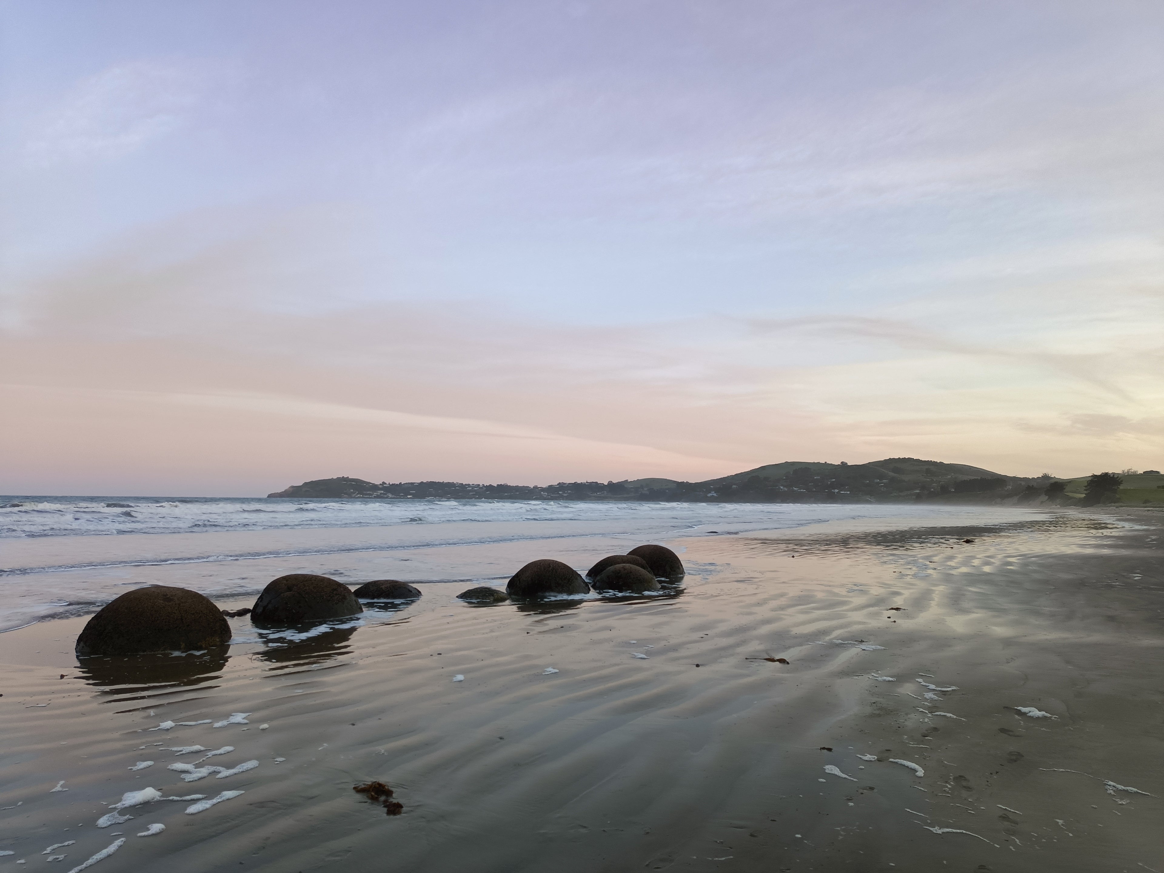 Round boulders on the beach at Moeraki, a famous geological site in New Zealand.